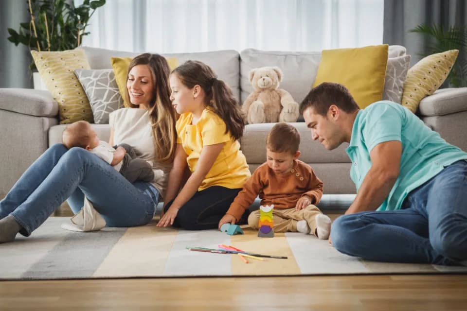 Salonun halısında birlikte oynayan bir aile