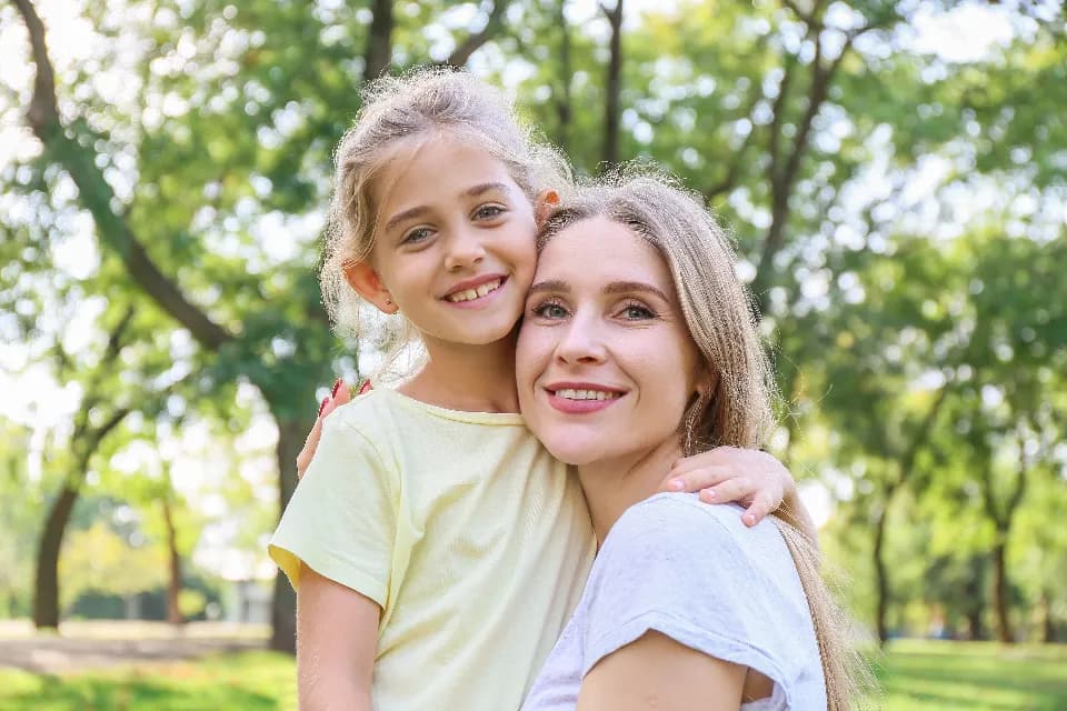 Ağaçların altında birbirine sarılan anne ve kızı