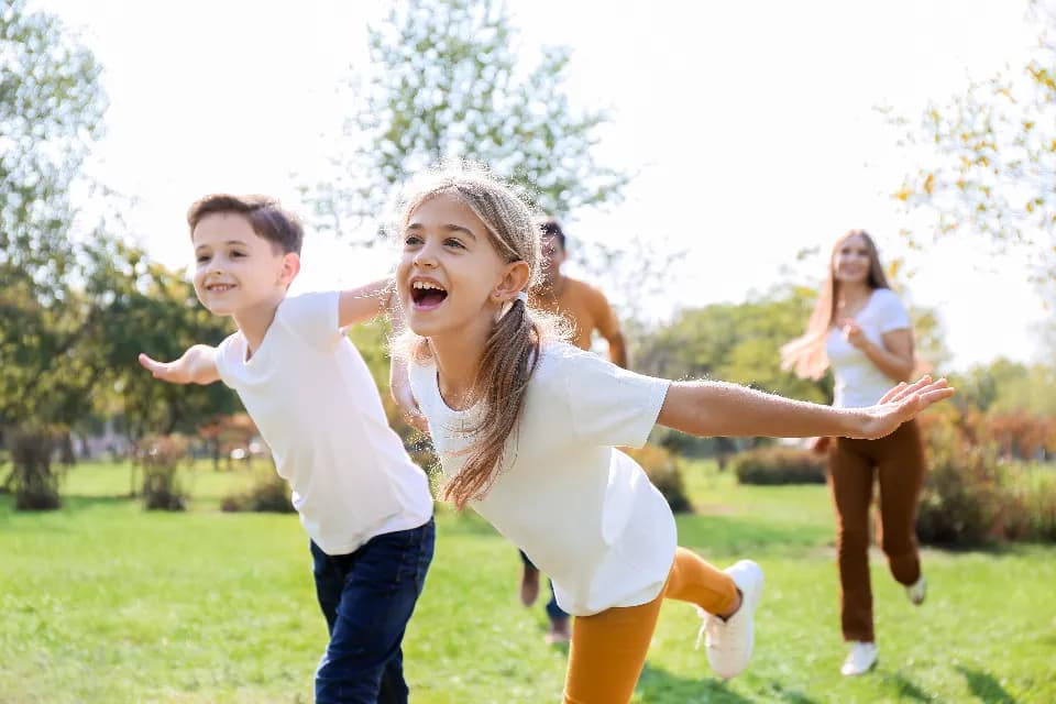Parkta kollarını açıp koşan çocuklar